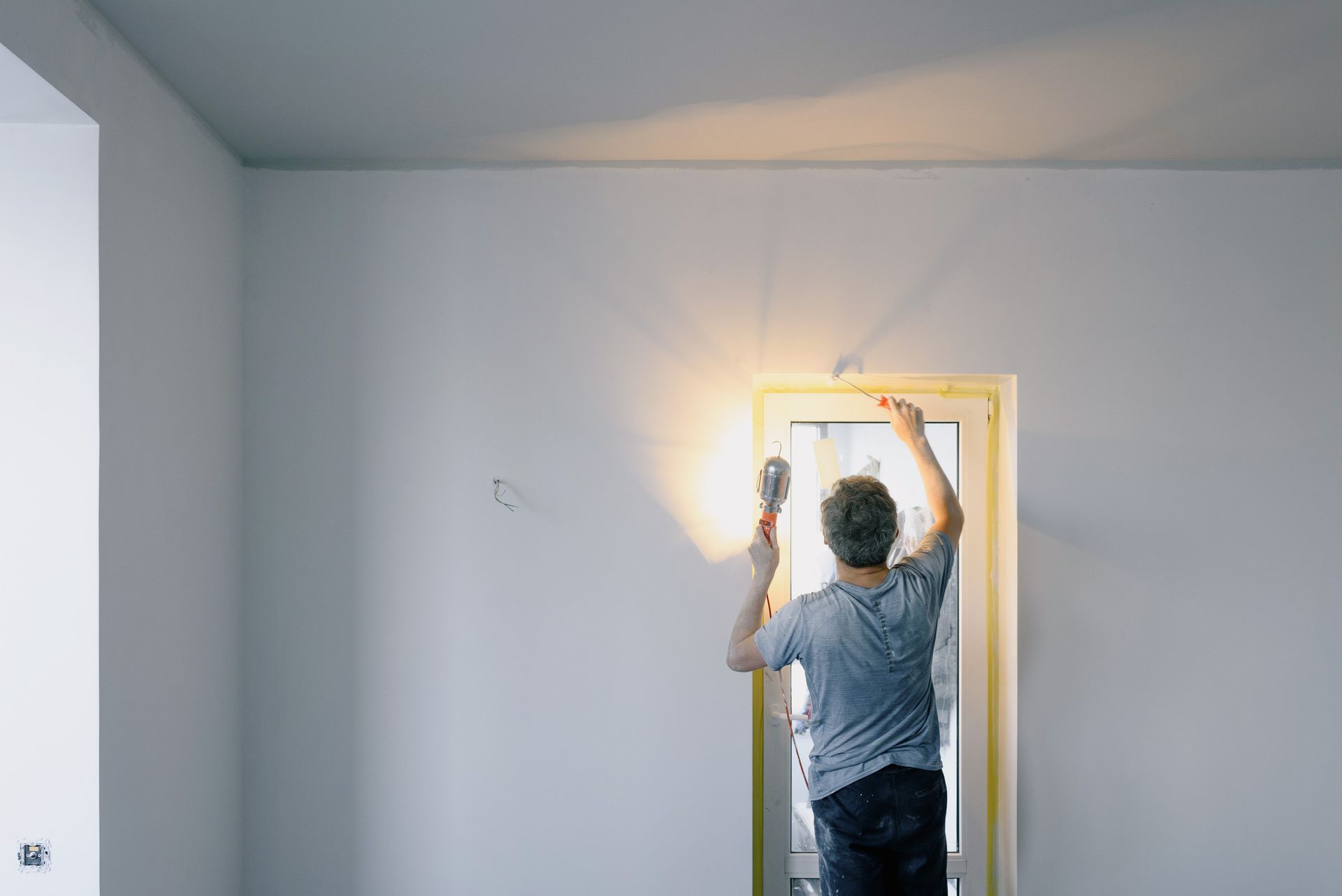 Handwerker bei Renovierungsarbeiten an einem Fenster – Symbolfoto